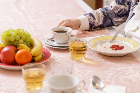 Pöydällä on aamiaistarpeita: puurolautanen, hedelmiä, kahvikuppi ja mehua.