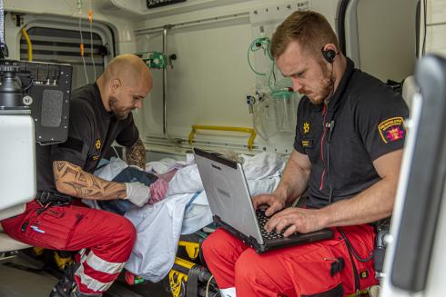 Två ambulanssjukvårdare behandlar patienten i ambulansen.