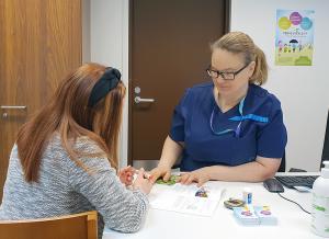 Potilas tutustuu hoitomateriaaleihin yhdessä diabeteshoitajan kanssa.